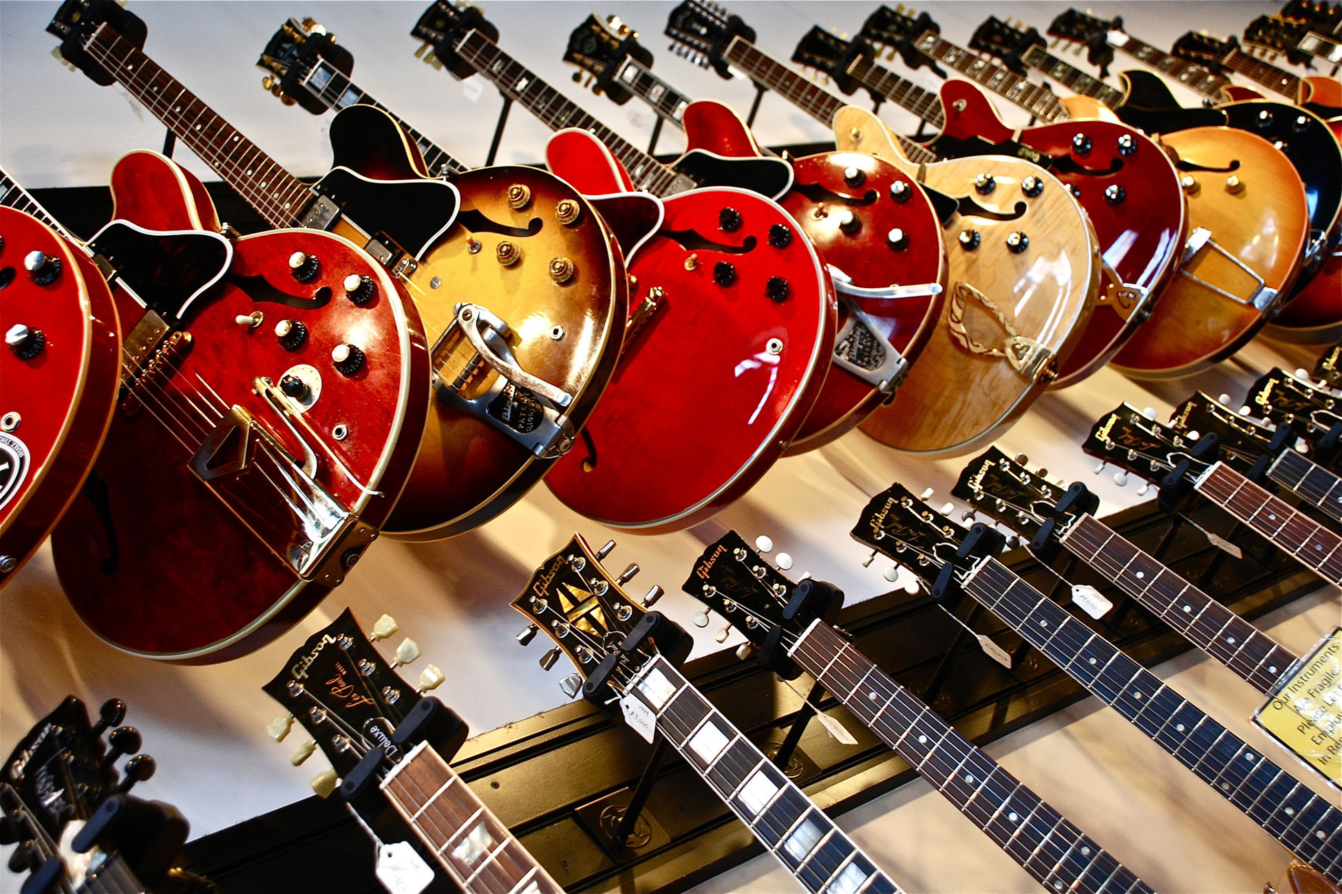 A bunch of Gibson guitar hanging in a wall