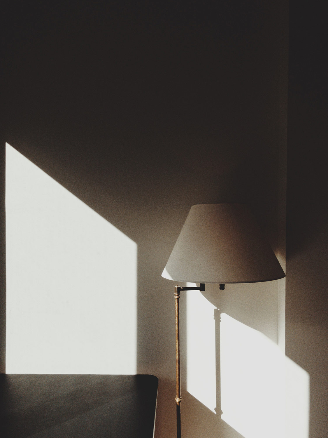 White lamp next to a black desk with sunlight shining through