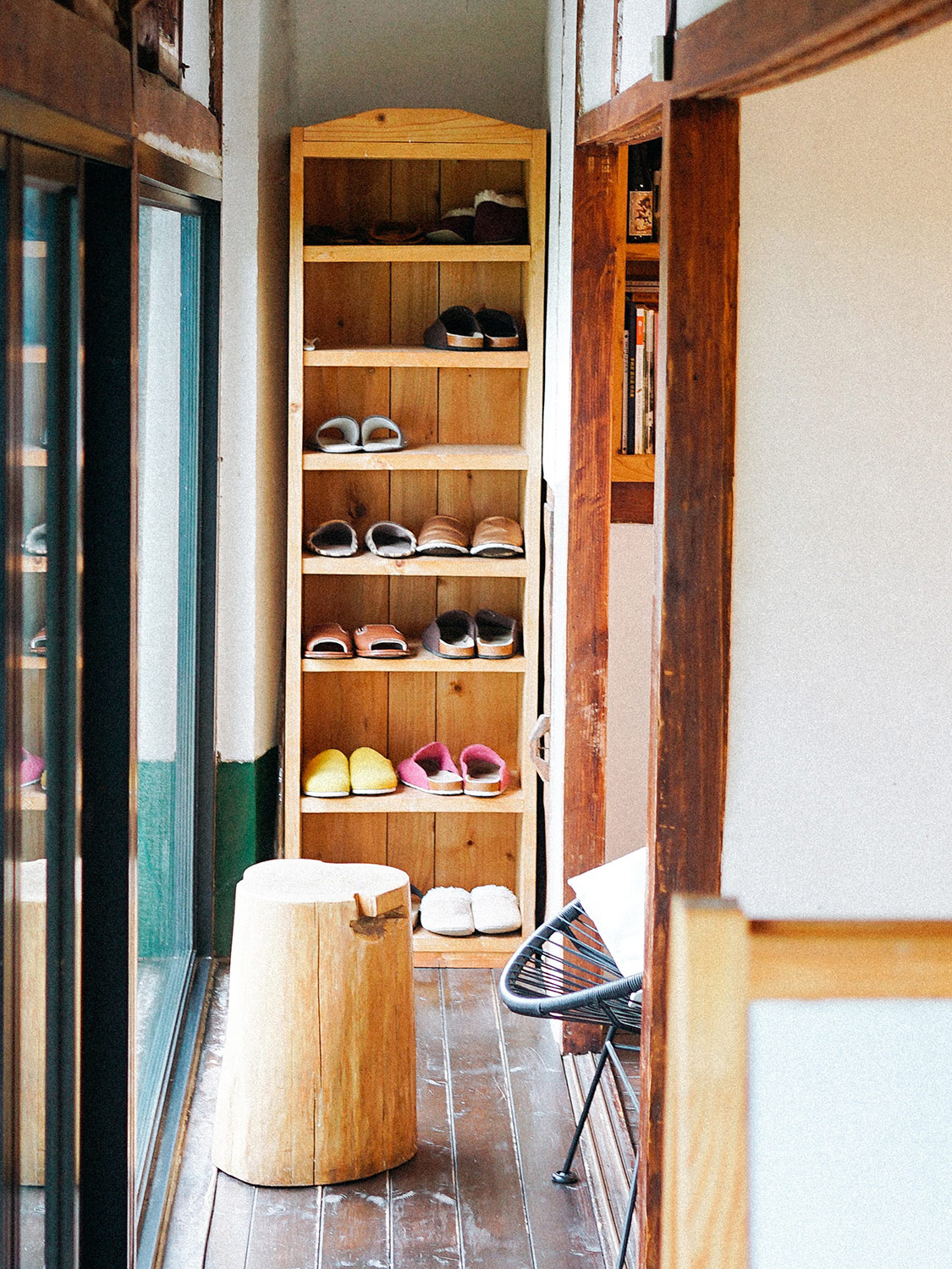 Lots of shoes on a wooden shoe rack by the frontdoor of a home